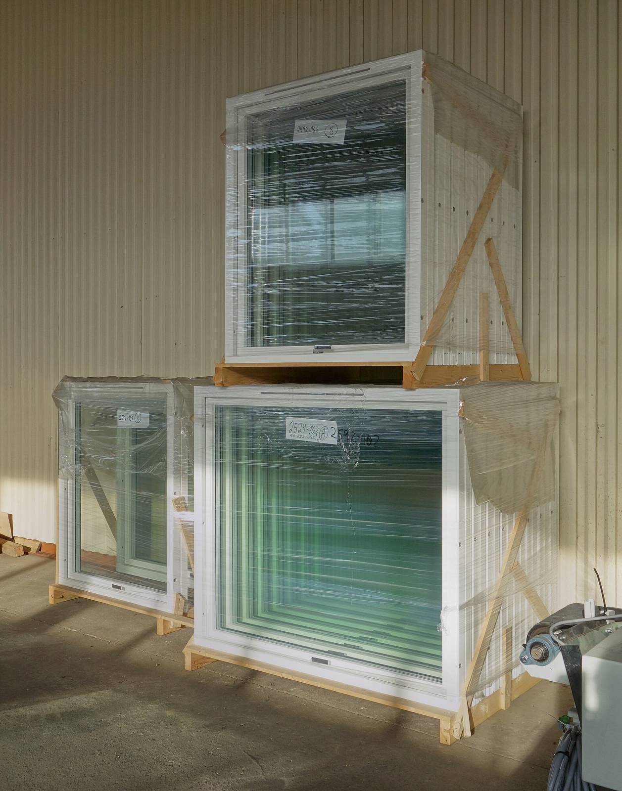 Nieuwe ramen in plastic folie verpakt op houten pallets, klaar voor levering in een magazijn